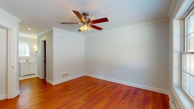 empty room with wood-type flooring, ceiling fan, crown molding, and a baseboard radiator