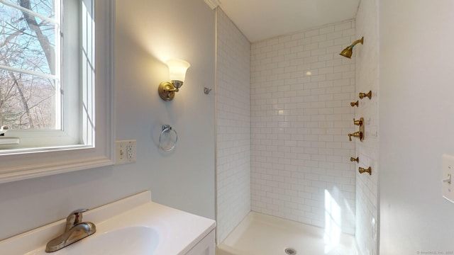 bathroom with tiled shower and vanity