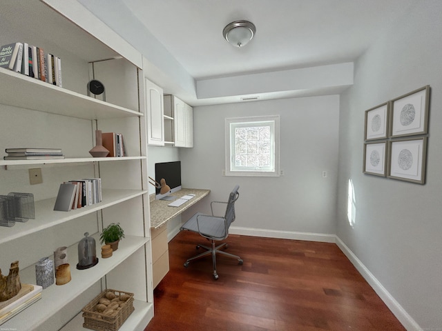 office with dark hardwood / wood-style floors and built in desk