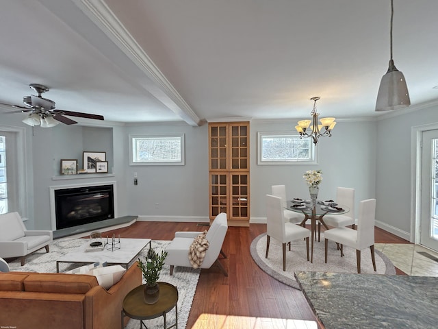 living room featuring crown molding, dark hardwood / wood-style floors, ceiling fan with notable chandelier, and a healthy amount of sunlight