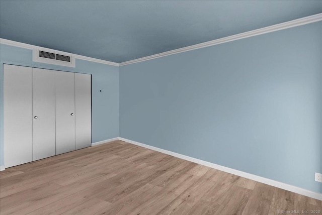 unfurnished bedroom featuring ornamental molding, a closet, and light hardwood / wood-style flooring