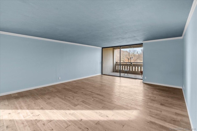 spare room with crown molding, a wall of windows, and light hardwood / wood-style flooring