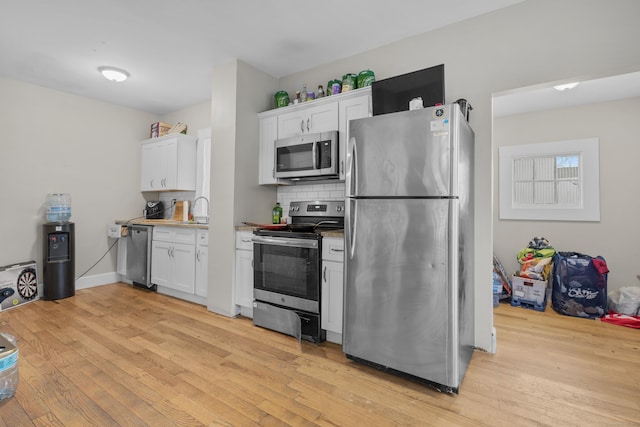 kitchen with sink, tasteful backsplash, stainless steel appliances, light hardwood / wood-style floors, and white cabinets