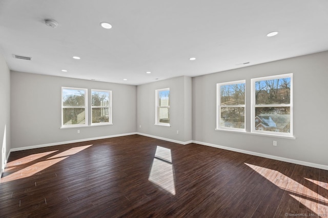 spare room featuring dark wood-type flooring and plenty of natural light