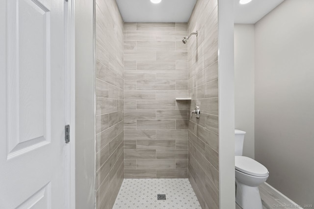 bathroom featuring a tile shower and toilet