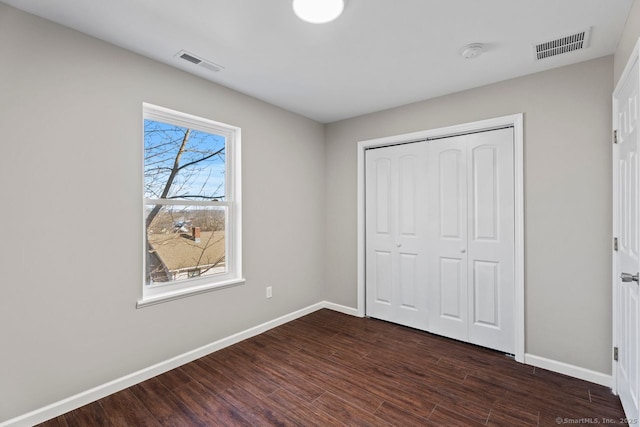 unfurnished bedroom featuring dark hardwood / wood-style flooring and a closet