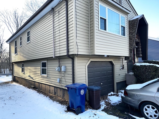 snow covered property with a garage