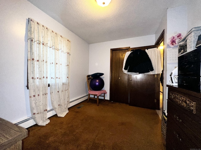 bedroom featuring a textured ceiling and dark colored carpet