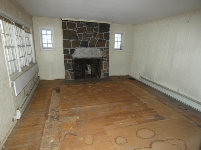 unfurnished living room featuring crown molding, a stone fireplace, a wealth of natural light, and baseboard heating