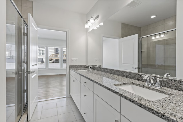 bathroom with tile patterned flooring, vanity, and a shower with door