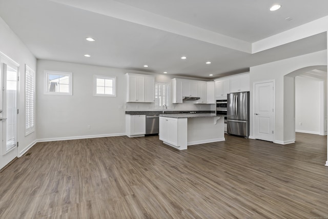 kitchen featuring appliances with stainless steel finishes, dark hardwood / wood-style floors, a kitchen island, and white cabinets