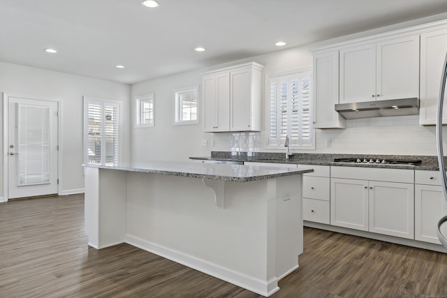 kitchen with white cabinetry, stone countertops, dark hardwood / wood-style flooring, and a center island