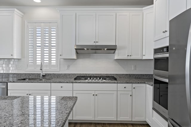 kitchen featuring stone counters, appliances with stainless steel finishes, sink, and white cabinets