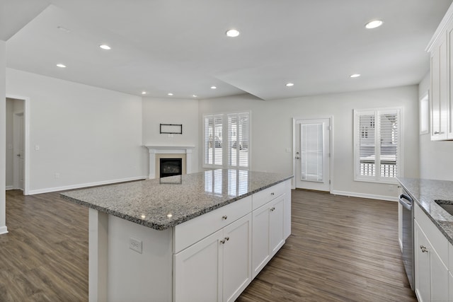 kitchen with stone countertops, white cabinetry, dark hardwood / wood-style flooring, a center island, and plenty of natural light