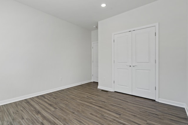 unfurnished bedroom with dark wood-type flooring and a closet