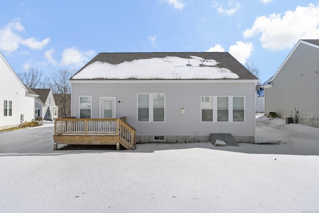 snow covered house with a wooden deck and cooling unit