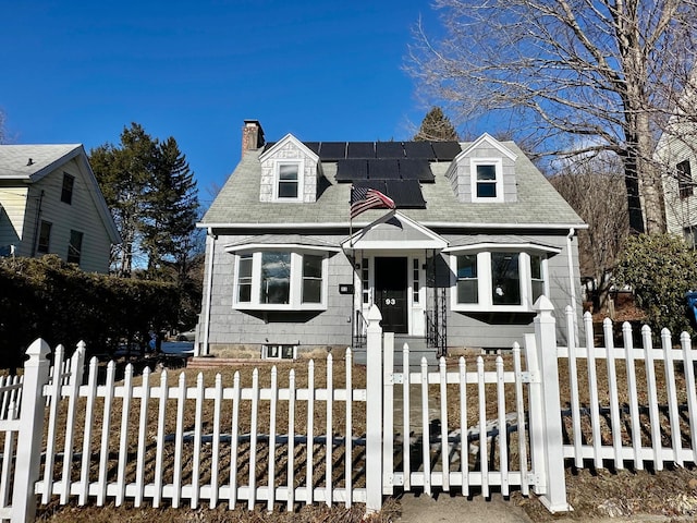 cape cod house featuring solar panels