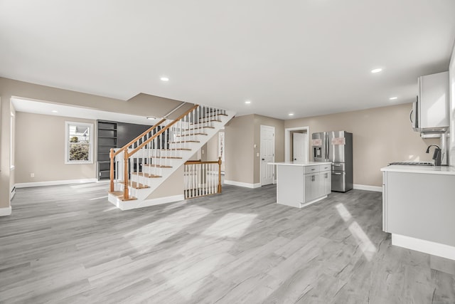 unfurnished living room featuring sink and light wood-type flooring