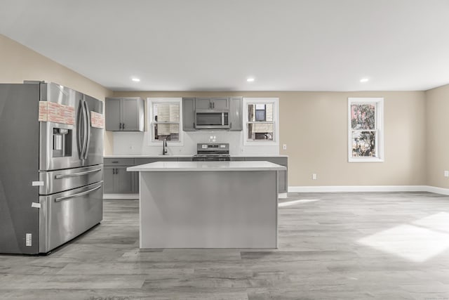 kitchen featuring sink, gray cabinetry, a center island, light wood-type flooring, and stainless steel appliances