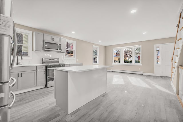 kitchen featuring a baseboard radiator, appliances with stainless steel finishes, a center island, and gray cabinetry