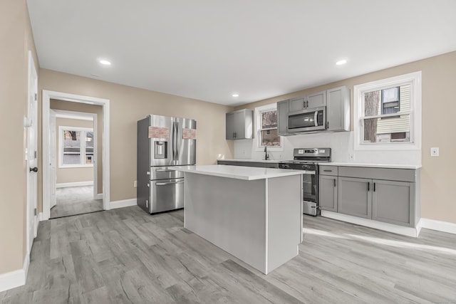 kitchen featuring a center island, stainless steel appliances, gray cabinets, and light hardwood / wood-style floors