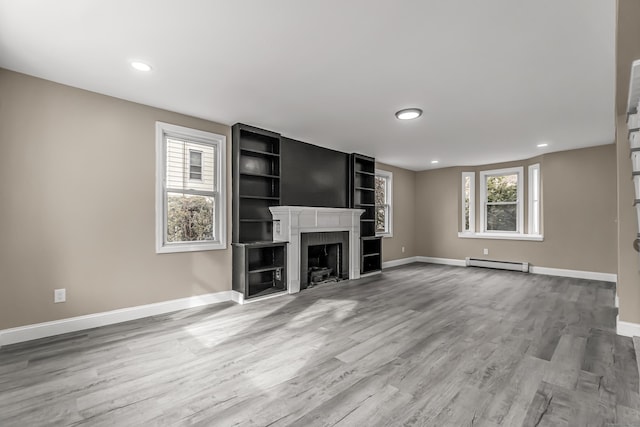 unfurnished living room featuring baseboard heating and wood-type flooring