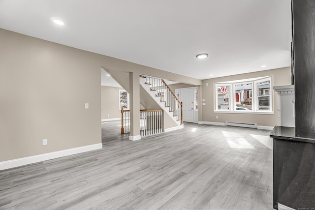 unfurnished living room featuring a baseboard radiator and light hardwood / wood-style floors