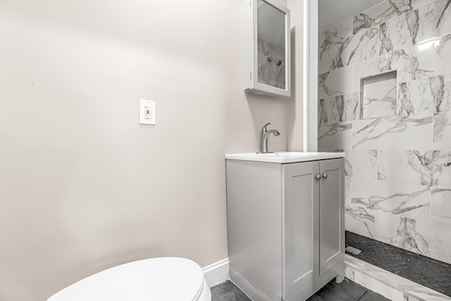 bathroom with vanity, toilet, and tiled shower