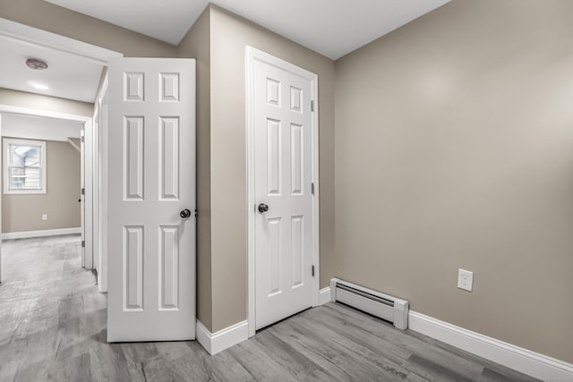 corridor featuring baseboard heating and light hardwood / wood-style floors