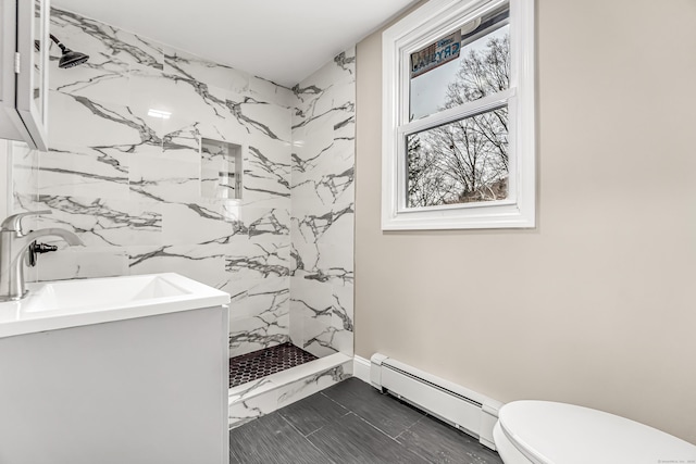 bathroom featuring vanity, a tile shower, baseboard heating, and toilet