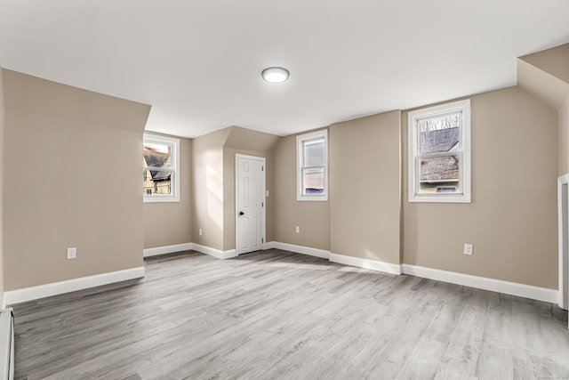 bonus room with lofted ceiling, a wealth of natural light, and light hardwood / wood-style floors