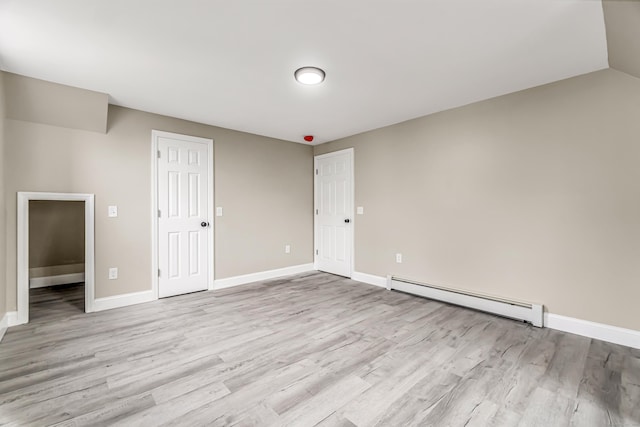 unfurnished room with light wood-type flooring, vaulted ceiling, and baseboard heating