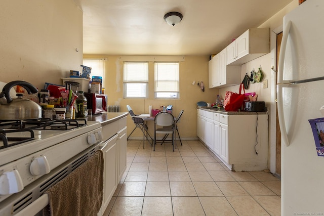 kitchen featuring light tile patterned flooring, white cabinets, and white appliances