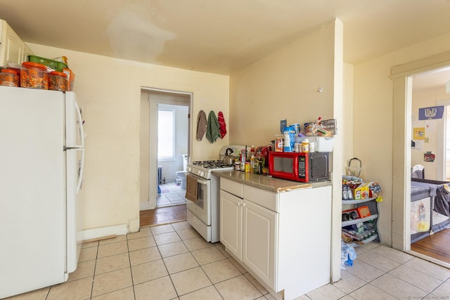 kitchen featuring white cabinetry, white appliances, and light tile patterned flooring