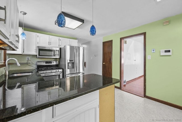 kitchen featuring white cabinetry, decorative light fixtures, kitchen peninsula, and appliances with stainless steel finishes