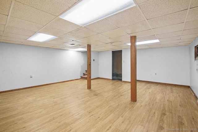 basement with a paneled ceiling and light wood-type flooring