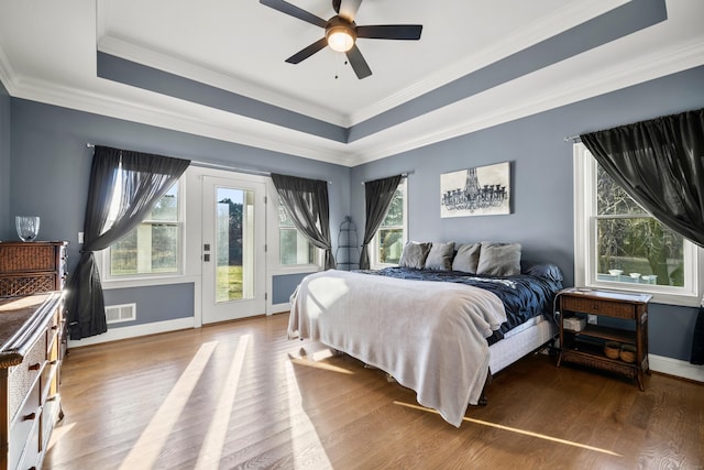 bedroom with hardwood / wood-style floors, access to exterior, ceiling fan, and a tray ceiling