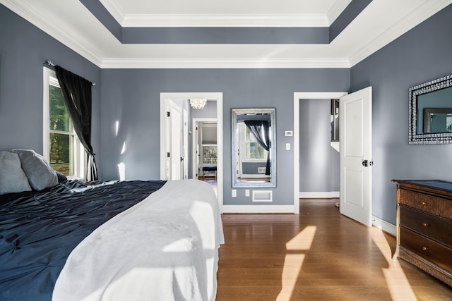 bedroom with dark hardwood / wood-style floors, a tray ceiling, and crown molding