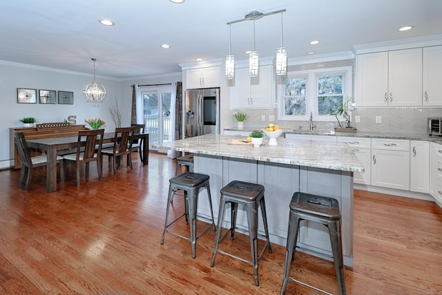 kitchen featuring a center island, pendant lighting, white cabinets, and stainless steel fridge with ice dispenser