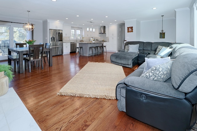 living room featuring dark wood-type flooring, ornamental molding, and an inviting chandelier