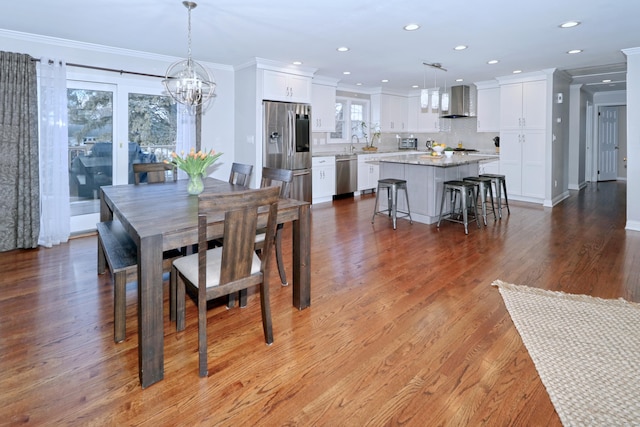 dining area featuring ornamental molding, wood-type flooring, sink, and a notable chandelier