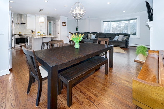 dining room with a baseboard heating unit, crown molding, wood-type flooring, and a notable chandelier