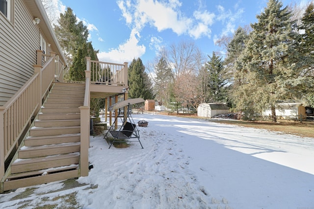 yard covered in snow with a shed and a wooden deck