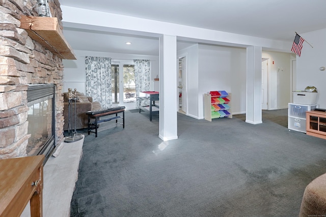 basement with a stone fireplace and dark colored carpet