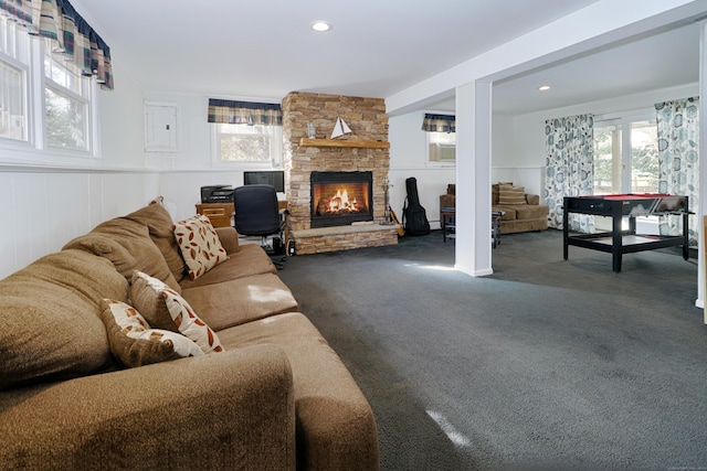 living room with dark carpet, a fireplace, and a healthy amount of sunlight