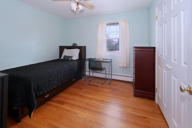 bedroom featuring a baseboard heating unit, light hardwood / wood-style floors, and ceiling fan