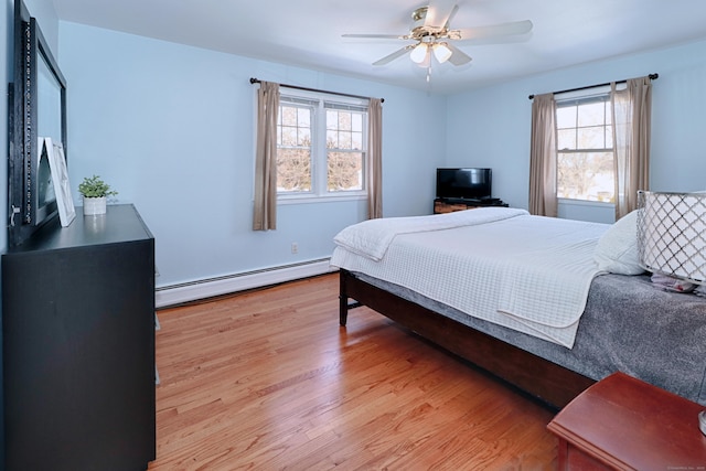 bedroom with baseboard heating, ceiling fan, light hardwood / wood-style floors, and multiple windows