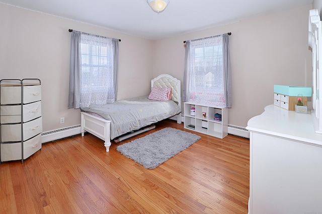 bedroom with a baseboard radiator and light hardwood / wood-style flooring