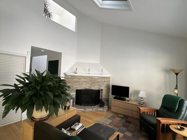 living room with a fireplace, a towering ceiling, a skylight, and wood-type flooring