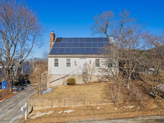 view of home's exterior with a chimney and solar panels